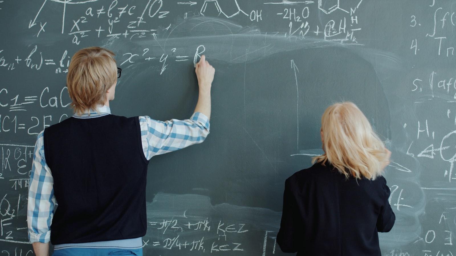 A student writing at a classroom desk
